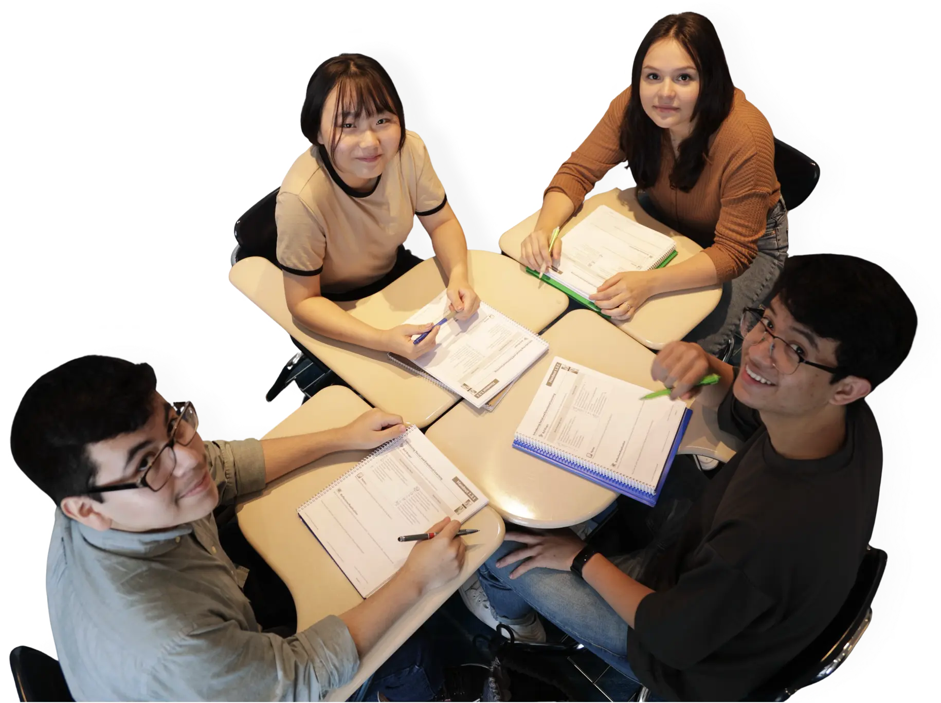 Two teen girls and two teen boys sitting at desks smiling