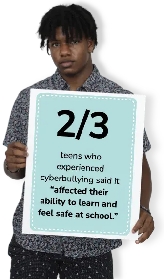 Teen boy with a neutral expression holding a poster showing a statistic on cyberbullying