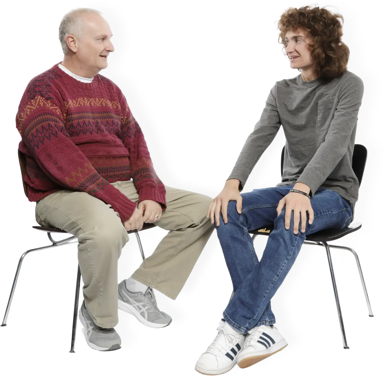 Male teacher and male student sitting in chairs facing each other talking
